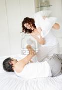 67067652092-portrait-of-happy-mature-couple-fighting-with-pillows-in-bed--indoor.